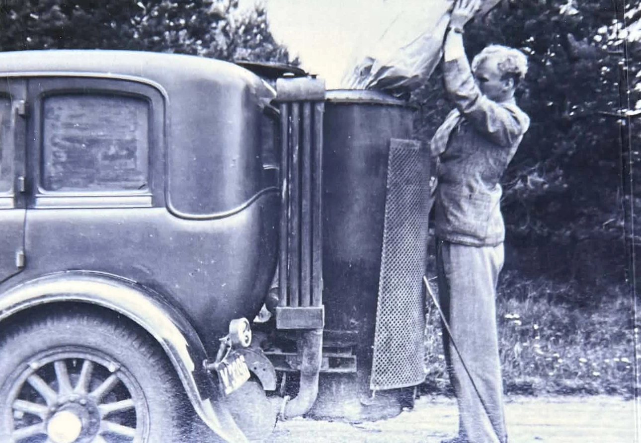 Historisk fotografi af en mand ved et køretøj fra bagsiden af Jydsk Genkul.